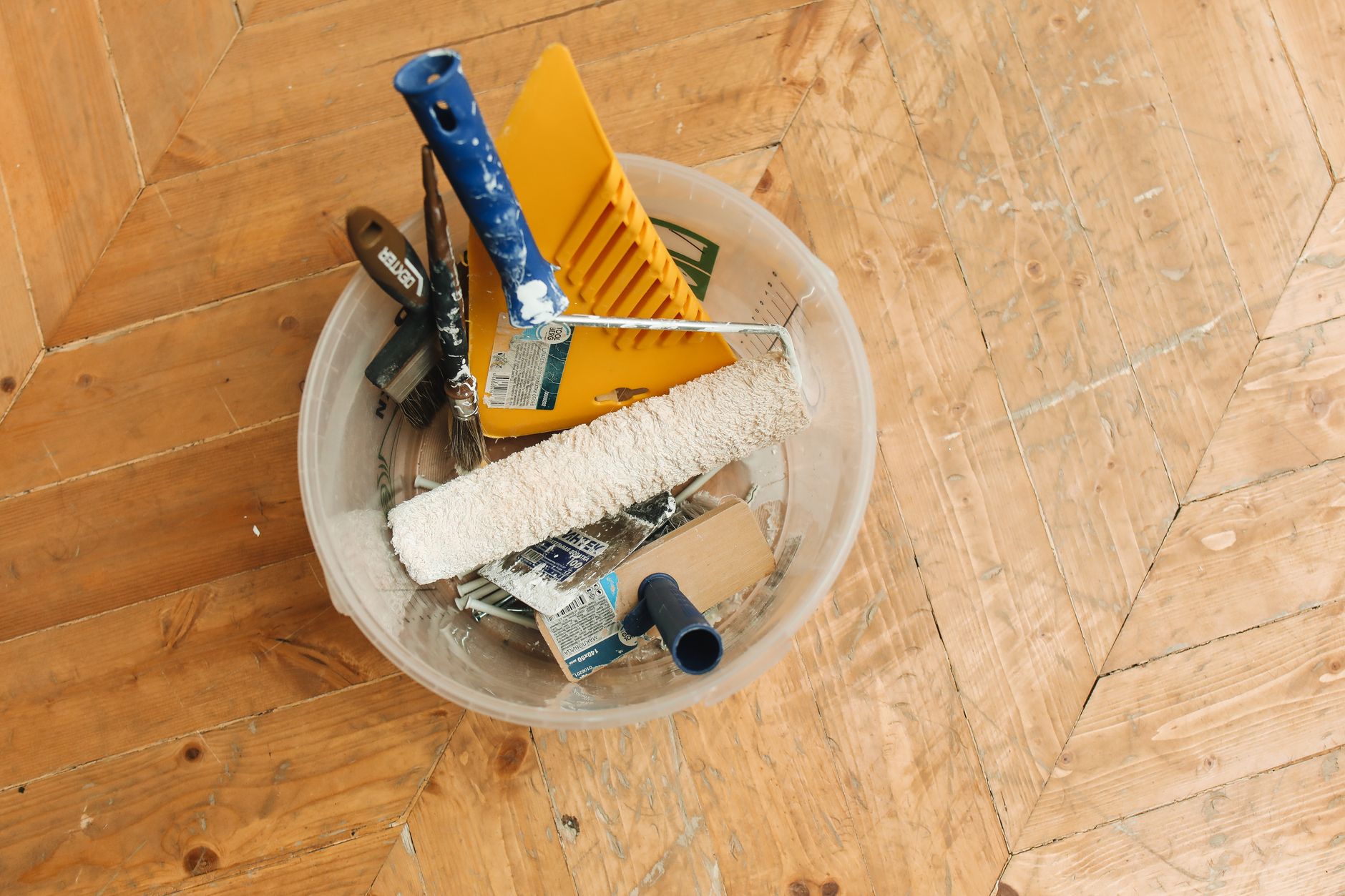 A collection of home renovation tools in a bucket on a wooden floor, ready for a painting project. — Security Fencing for Hom