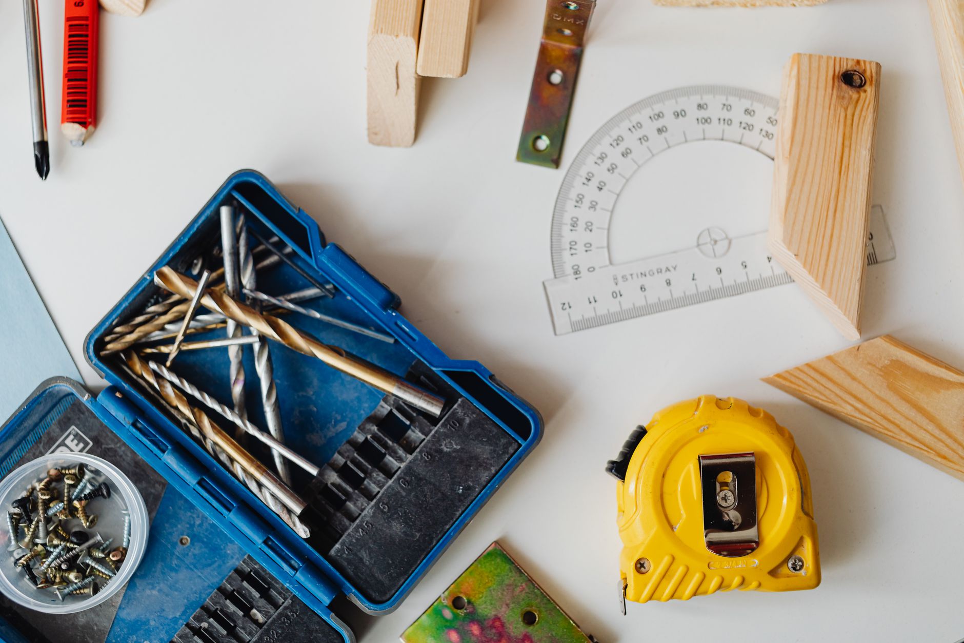 A selection of carpentry tools including drill bits, measuring tape, and protractor in an overhead shot. — Your Complete Guid